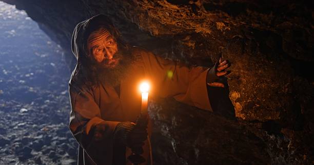 istock A Mysterious Figure Holding a Flickering Candle in a Dark and Enigmatic Cave Environment 2205099232