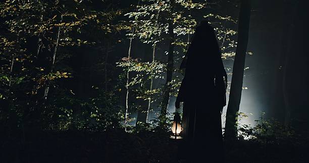 istock A Mysterious and Eerie Figure Wandering Through a Dark Forest Holding a Lantern Light 2205099550