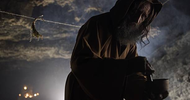 A mysterious cloaked figure in a dimly lit cave gathers intriguing ingredients under the ethereal celestial glow