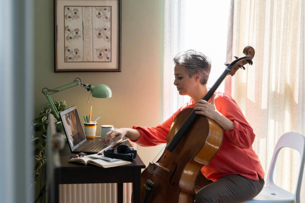 istock Woman Watching A Tutorial On Laptop On How To Play Cello 2205100011
