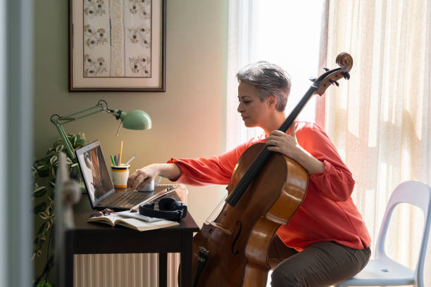 istock Woman Watching A Tutorial On Laptop On How To Play Cello 2205100012