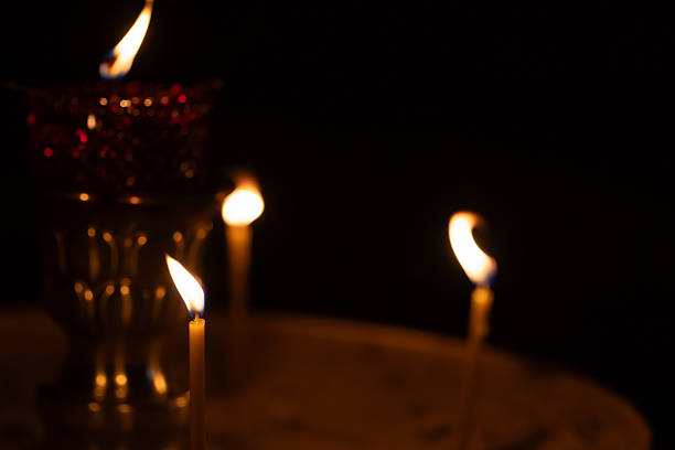 Few lit candles glowing dimly in a serene, religious environment creating an ambiance of spirituality and tranquility. Selective soft focus