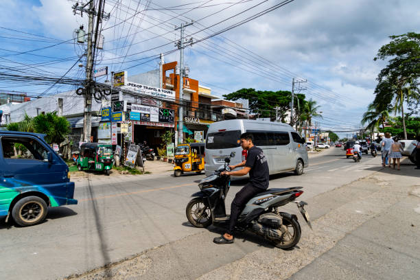 Alona Beach, Main Street, Philippines, January 2025:  Traffic including, cars, tuk tuks and motorcycles on the main road through Alona Beach.