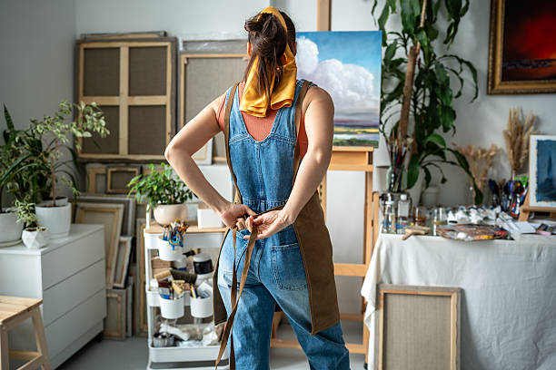 Woman painter tying apron getting ready for creative work. Female artist at art workshop