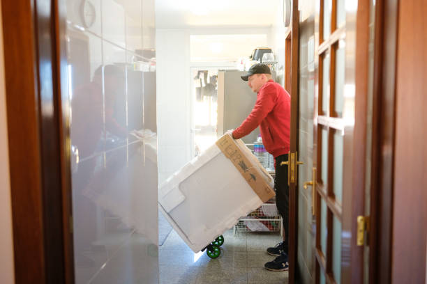 Delivery man carefully moving a new refrigerator into a kitchen using a hand truck