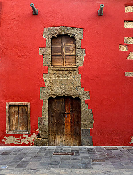 istock Cannons guarding vibrant red facade with rustic wooden doors and windows in tenerife 2205108280