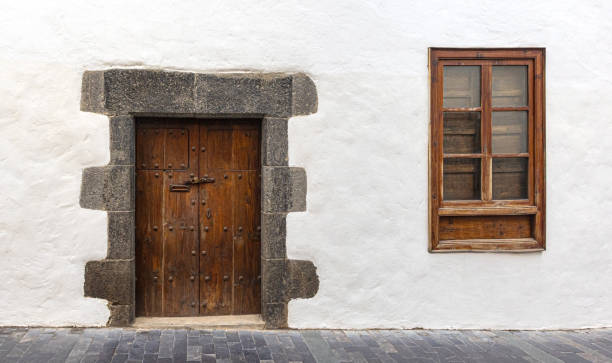 istock Old wooden door and window set in white wall 2205108295