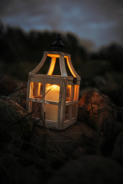 istock Close-up of a Glowing Candle in a Rustic Lantern Among Rocks at Night 2205108876