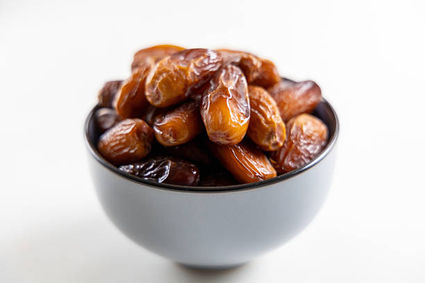 Delicious dates in a bowl on white