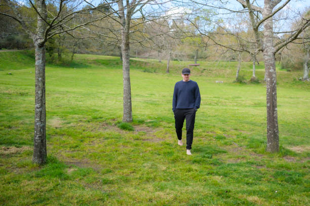 istock Young man walking barefoot on grass in a park enjoying nature 2205109718