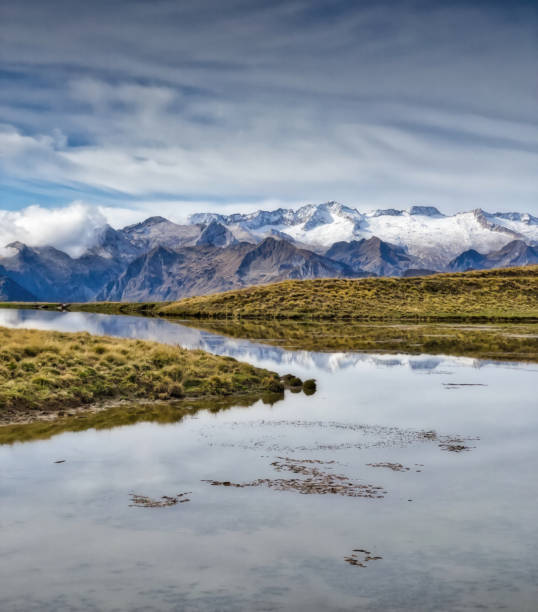 istock Pyrenees mountains reflecting in a peaceful lake under cloudy sky. 2205111051
