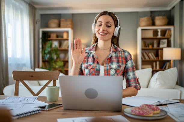 istock Architect waving to colleagues during online meeting from home office 2205111622