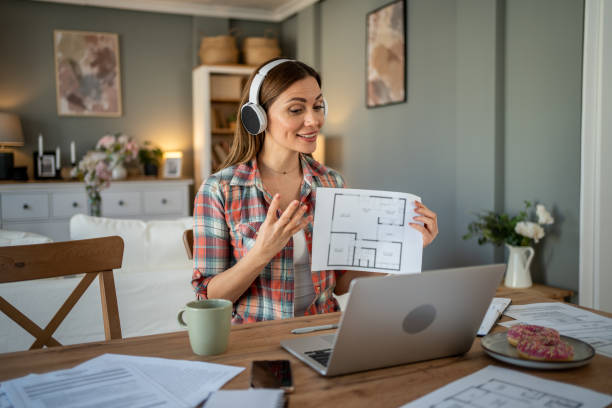 istock Architect showing blueprint during video call at home office 2205111647