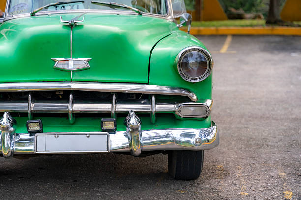 Close-up of a green vintage American car from the 1950s in Cuba, featuring chrome details and a distinctive front grille.