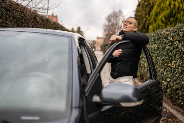 istock Man Relaxing Outdoors Next to His Car on a Peaceful Street 2205113048