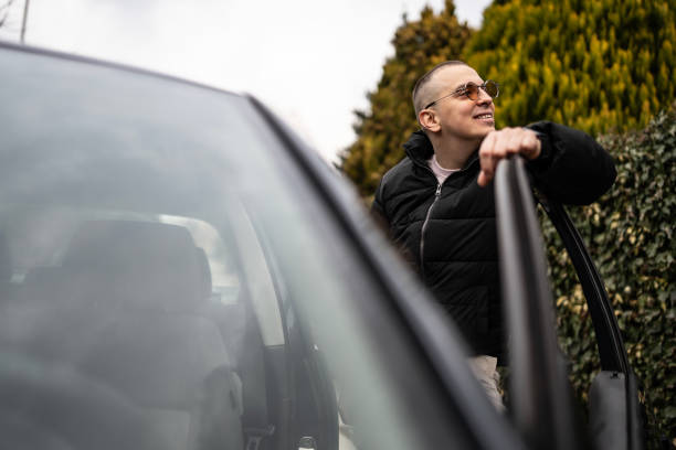 istock Young Man Opening Car Door Outdoors on a Bright Day 2205113078