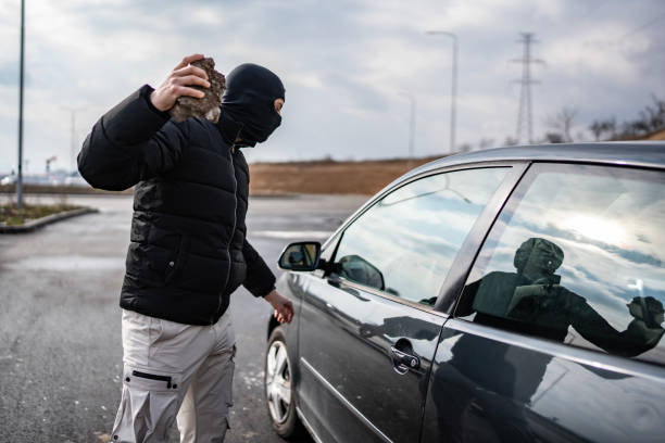 istock Masked Individual Threatening Car with Stone on Empty Road in Daylight 2205113181