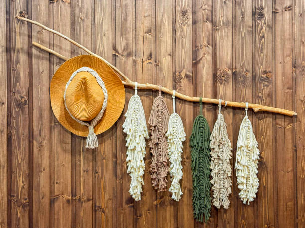 istock Boho style wall decor with a straw hat and macrame hanging on a wooden background. Cozy rustic interior decoration with natural textures 2205113754
