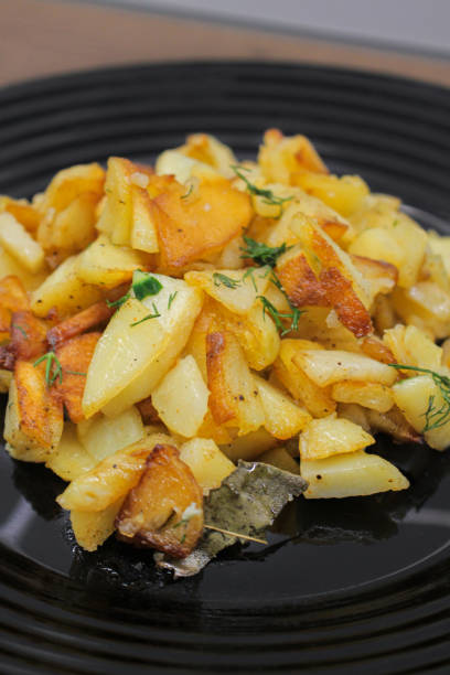 istock fried potatoes cut into pieces in a black plate with dill close-up 2205113776