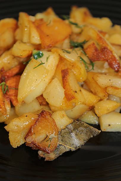 istock fried potatoes cut into pieces in a black plate with dill close-up 2205113783