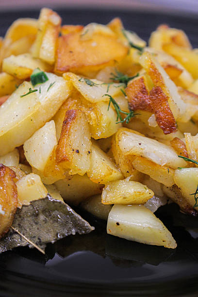 istock fried potatoes cut into pieces in a black plate with dill close-up 2205113784
