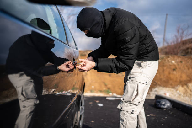 istock Masked Individual Attempting Unauthorized Entry into a Locked Vehicle Outdoors 2205113851