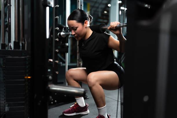 istock Woman performing squats with weights in gym 2205114318