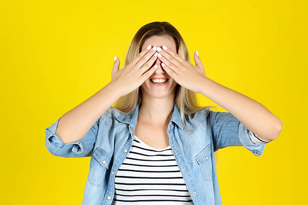 istock Young woman closing eyes by hands on yellow background 2205116912