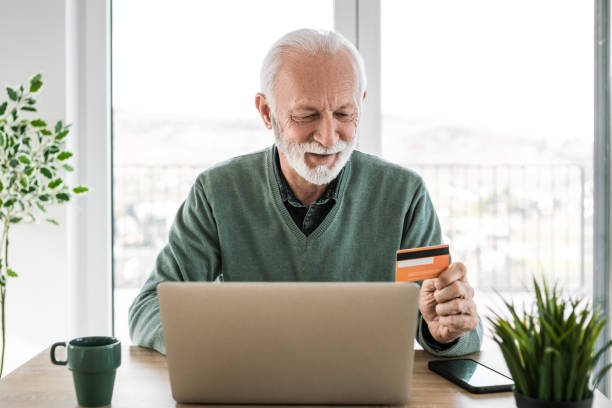 istock Man paying with credit card at home using laptop 2205117306