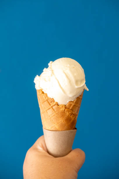 istock Milk ice cream in a waffle cone, with blue background 2205118320
