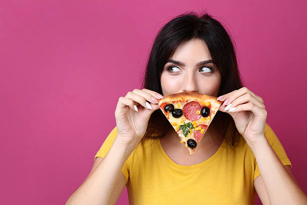 istock Young woman with pizza on pink background 2205121372