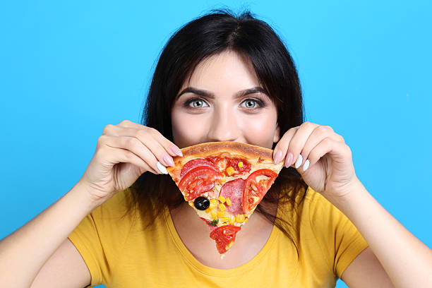 istock Young woman with pizza on blue background 2205121740