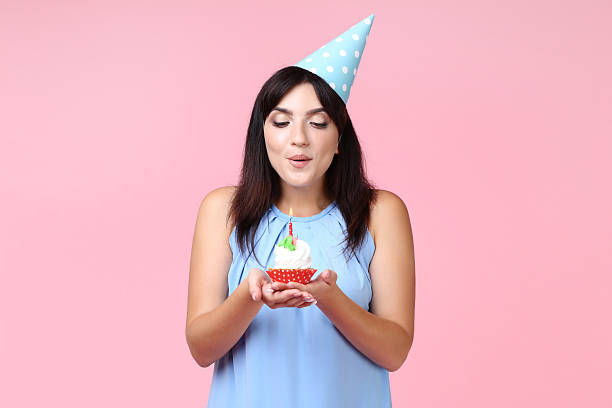 istock Young woman with birthday cupcake on pink background 2205122040