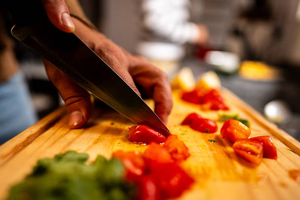 istock Close-up of man cutting tomatoes on cutting board 2205123022