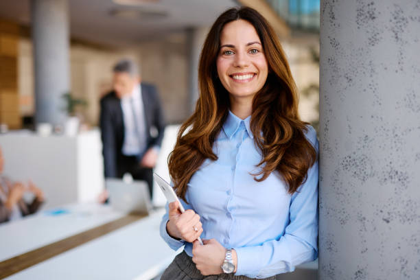 istock Young businesswoman smiling in modern office holding tablet 2205123587