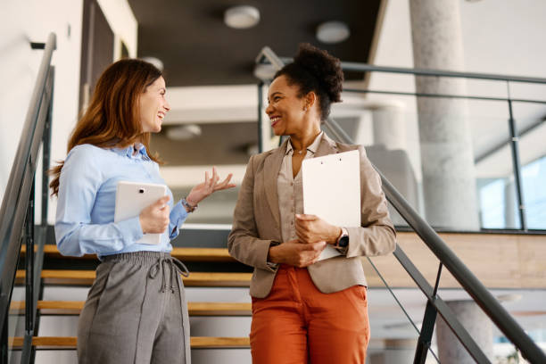 istock Two businesswomen talking on stairs in modern office 2205123717