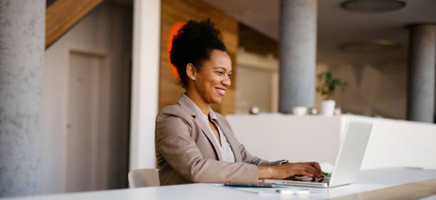 istock Smiling businesswoman working on laptop in modern office 2205123771