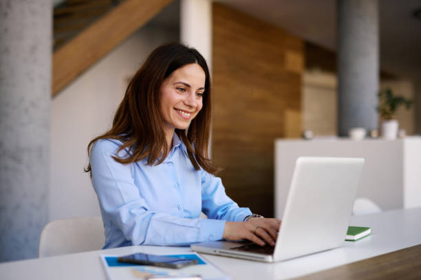 istock Smiling businesswoman working on laptop in modern office space 2205123799