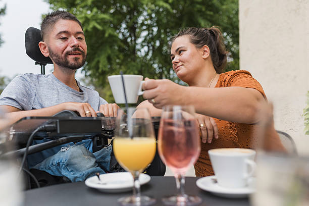 istock Girlfriend assisting her boyfriend with a disability to drink coffee in a cafe 2205124706