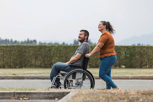 istock Man with a disability and his assistant having a great time together outdoors 2205124976