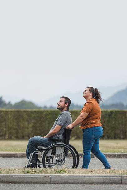 istock Man with a disability and his assistant having a great time together outdoors 2205125046