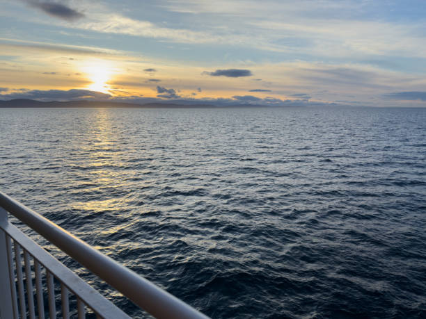 istock View from the water of the sun setting behind a mountain range 2205126410