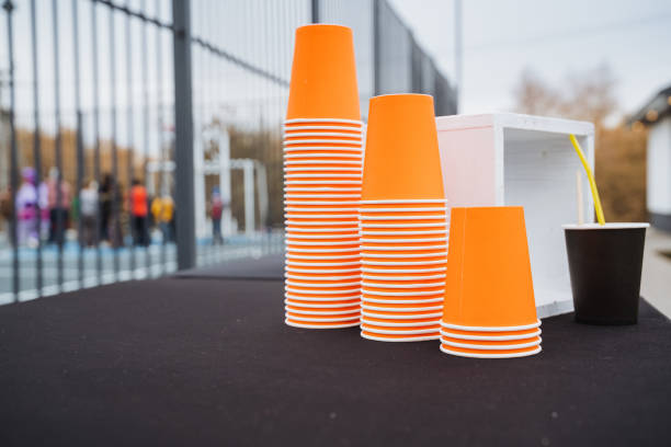 On a table, there are three distinct stacks of vibrant orange cups thoughtfully arranged, creating a playful and colorful display that draws the eye and livens up the surrounding space