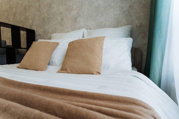 istock A bed with white sheets and brown pillows in a bedroom 2205126849