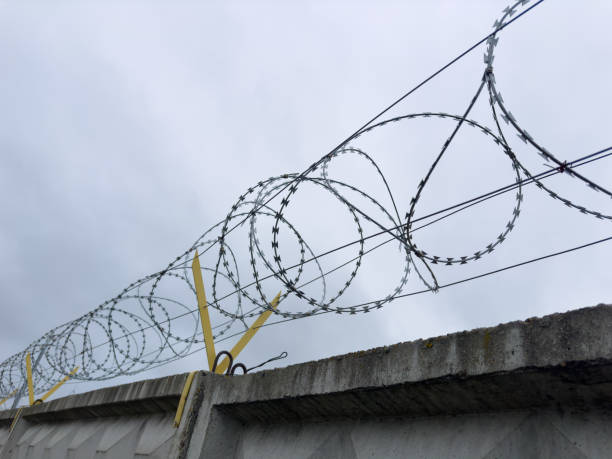 istock A barbed wire fence is securely attached to a sturdy concrete wall 2205127047