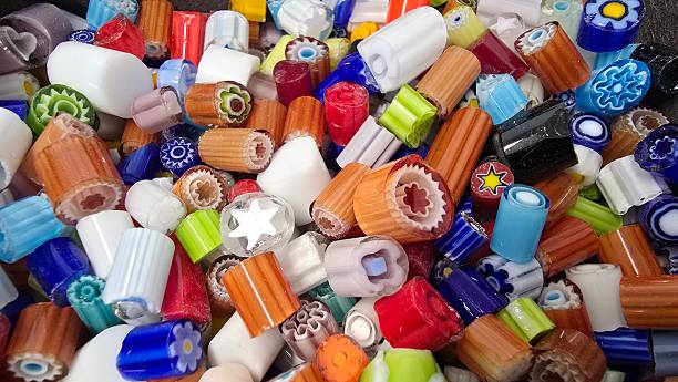 A colorful assortment of Murano glass beads, featuring intricate patterns and floral designs. The vibrant mix of shapes and hues creates a visually striking display of traditional glass craftsmanship.
