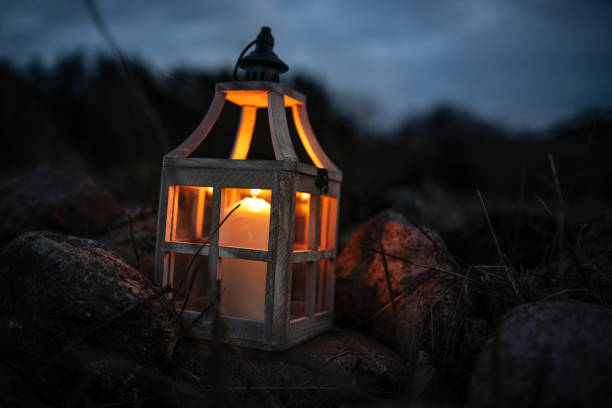 istock Close-up of a Glowing Candle in a Rustic Lantern Among Rocks at Night 2205128460