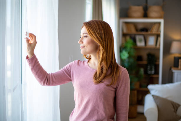 istock Beautiful smiling woman looking through the window 2205129443