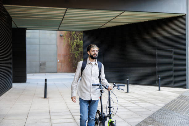 istock Businessman walking with folded bicycle in urban setting 2205133925