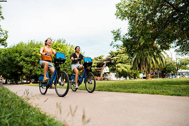 istock Sisters riding bikes in a public park 2205134022